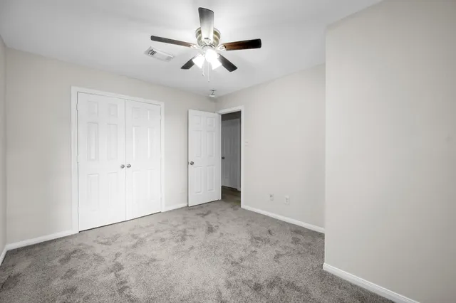 an empty room with a ceiling fan and a window
