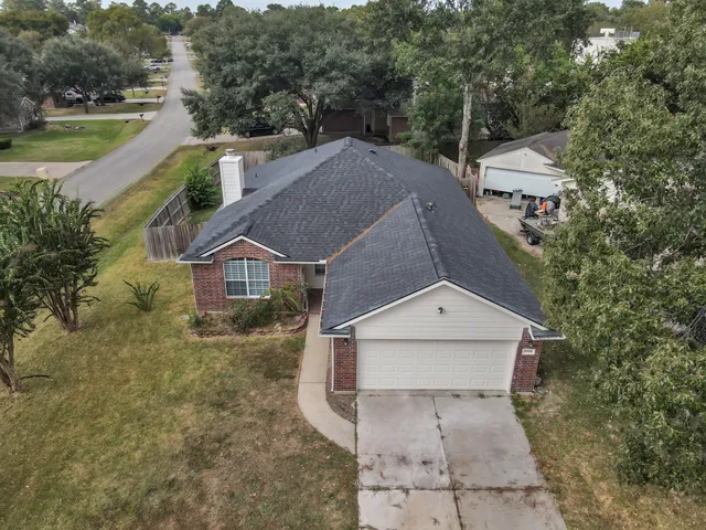 an aerial view of a house with swimming pool and large trees