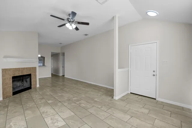 an empty room with fan and fireplace