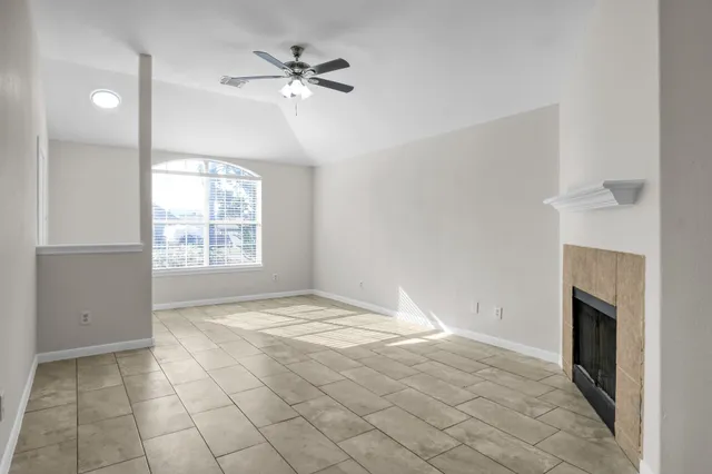 an empty room with windows and fireplace