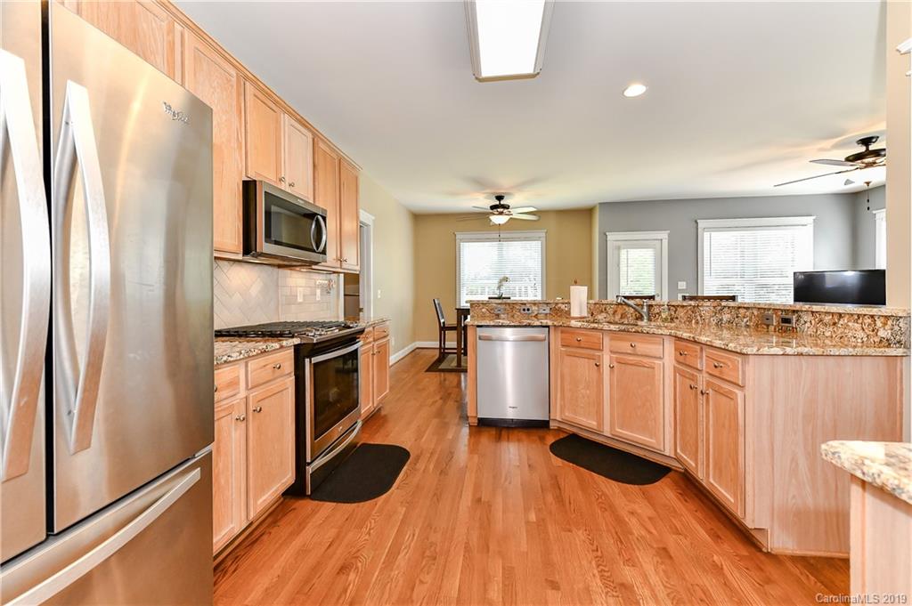 1036 Hunters Run Drive Tega Cay, SC 29708 - Photo 14 of 35 a kitchen with granite countertop a refrigerator oven a sink dishwasher and white cabinets with wooden floor