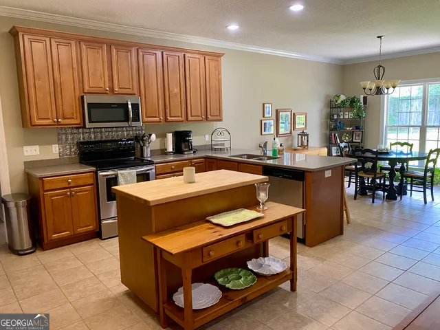 a kitchen with stainless steel appliances a stove a sink cabinets and a dining table