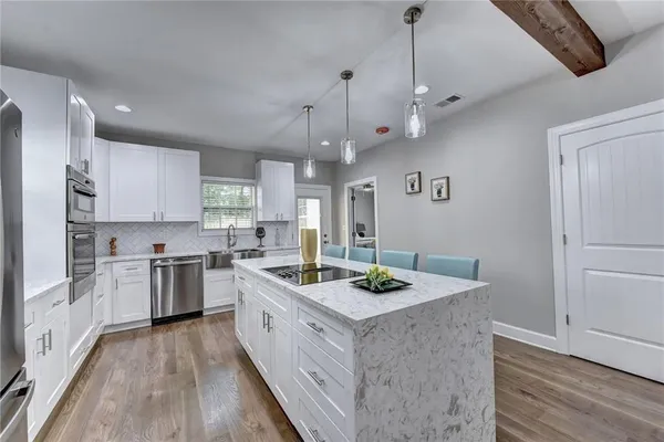 a kitchen with stainless steel appliances kitchen island granite countertop a sink stove and refrigerator