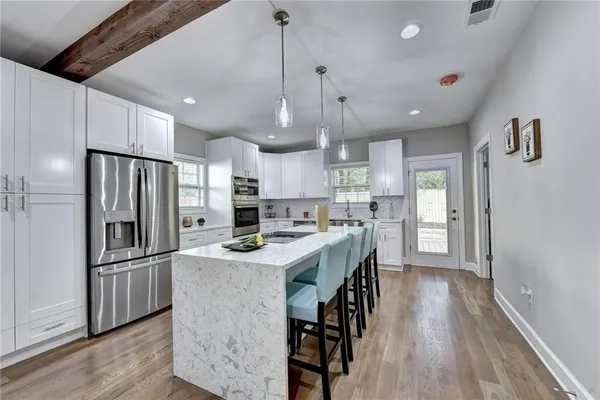 a kitchen with stainless steel appliances granite countertop a refrigerator a sink dishwasher a stove and a refrigerator with wooden floor