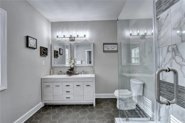 a bathroom with a double vanity sink a toilet a mirror and shower