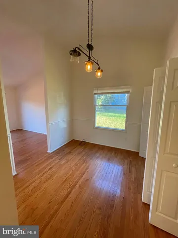 an empty room with wooden floor cabinet and windows