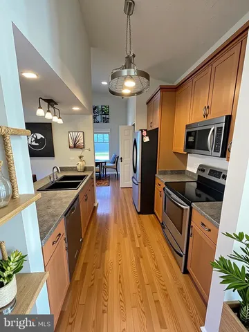 a kitchen with stainless steel appliances a refrigerator a stove top oven a sink dishwasher and wooden floor