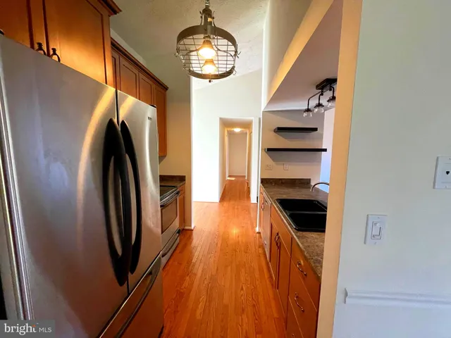 a kitchen with stainless steel appliances granite countertop a refrigerator a stove and a wooden floors