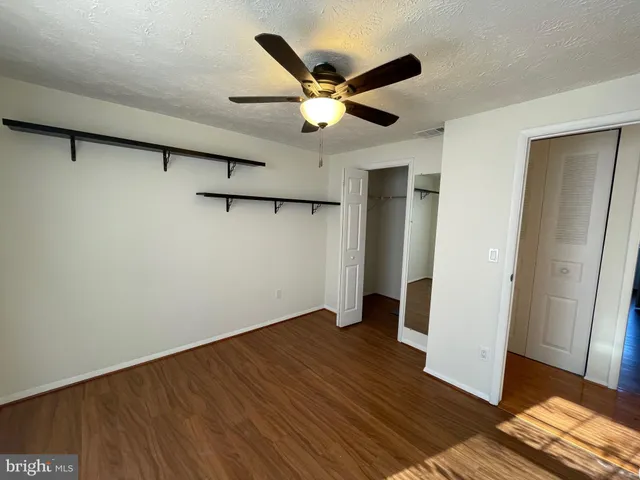 an empty room with wooden floor and a ceiling fan