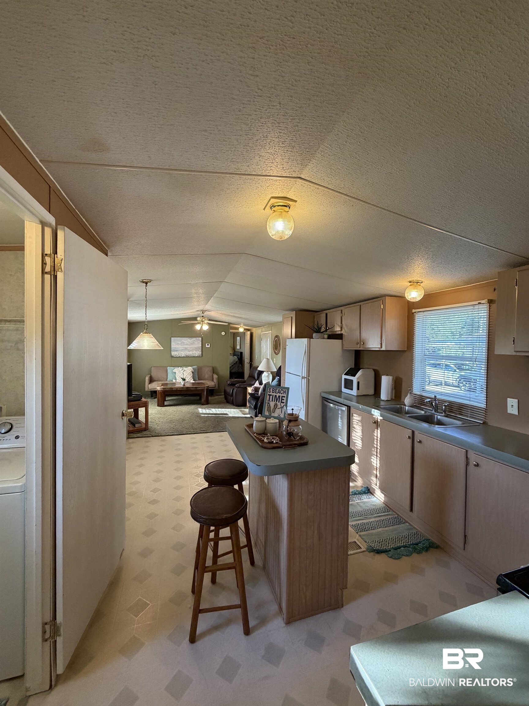 1125 Ridgewood Drive Lillian, AL 36549 - Photo 5 of 36 Kitchen with light wood-finish cabinetry, a double basin stainless steel sink, and a breakfast bar island featuring a light countertop