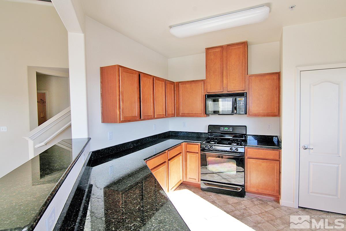 9050 Double R, Unit 225 Reno, NV 89521 - Photo 6 of 29 a kitchen with granite countertop a stove a sink and a microwave