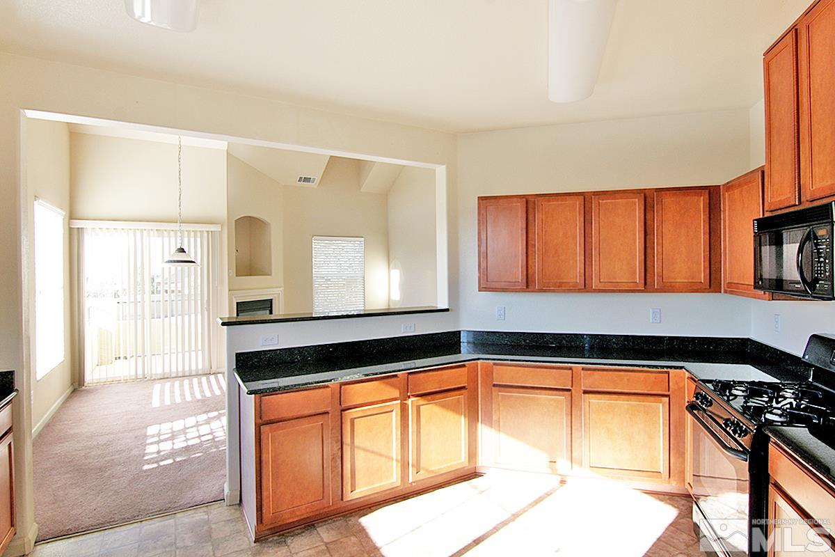9050 Double R, Unit 225 Reno, NV 89521 - Photo 7 of 29 a kitchen with granite countertop a stove a sink and a microwave