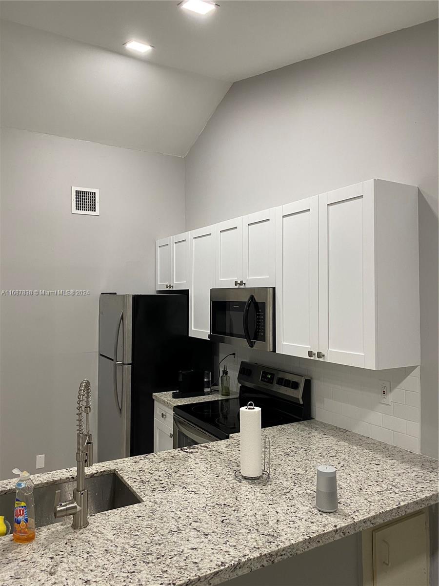 14010 Southwest 91st Terrace, Unit 14010 Miami, FL 33186 - Photo 2 of 6 a kitchen with a sink a stove and cabinets