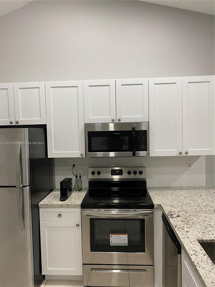 14010 Southwest 91st Terrace, Unit 14010 Miami, FL 33186 - Photo 3 of 6 a kitchen with a stove and a microwave