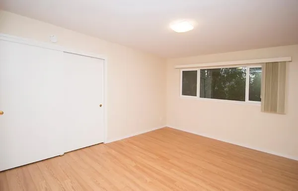 a view of a big room with wooden floor and windows
