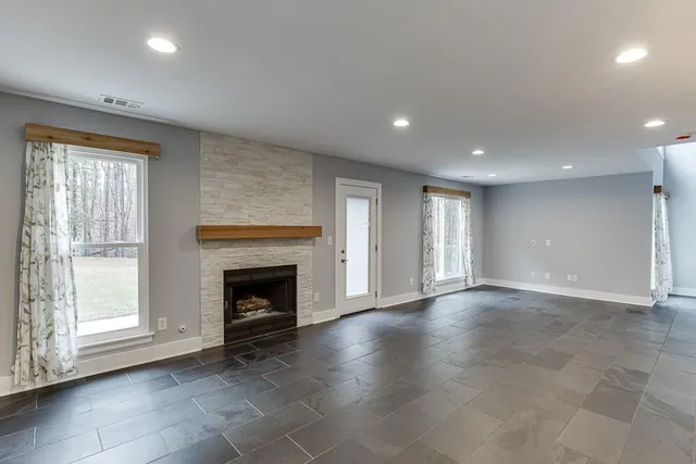 an empty room with windows and fireplace