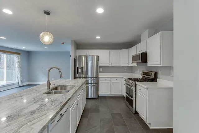 a kitchen with stainless steel appliances granite countertop a sink a stove top oven a counter space and cabinets