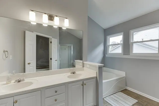 a bathroom with a toilet a sink a window and shower