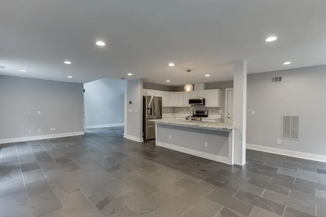 a view of kitchen with kitchen island a sink stainless steel appliances and cabinets