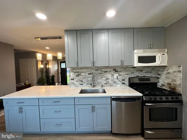 a kitchen with sink a microwave a stove and cabinets