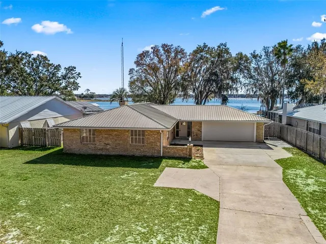 a view of a house with a yard and large trees