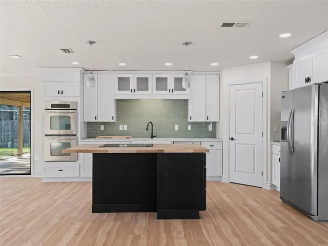 a kitchen with stainless steel appliances kitchen island granite countertop a stove a sink and a refrigerator