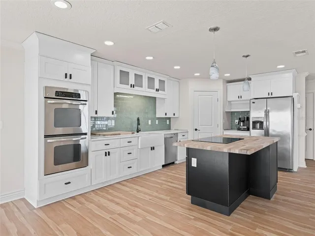 a kitchen with cabinets stainless steel appliances and wooden floor