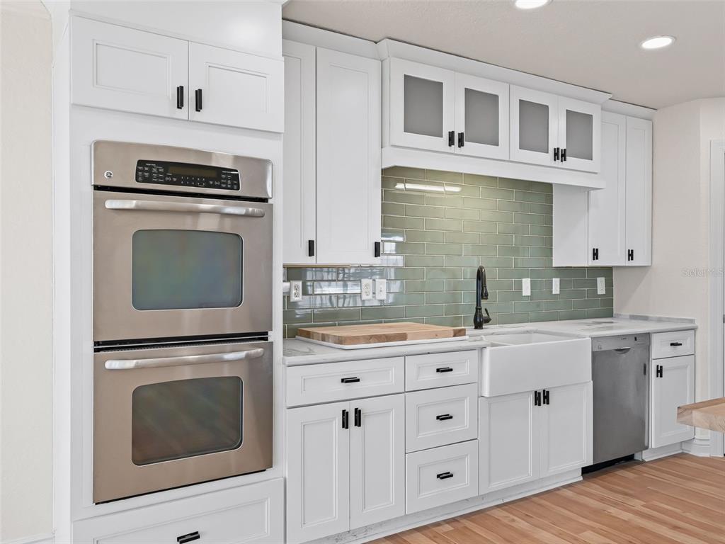 10916 Southeast Timucuan Road Summerfield, FL 34491 - Photo 13 of 40 a kitchen with cabinets stainless steel appliances and wooden floor