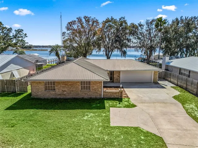 a view of a house with a yard plants and large tree