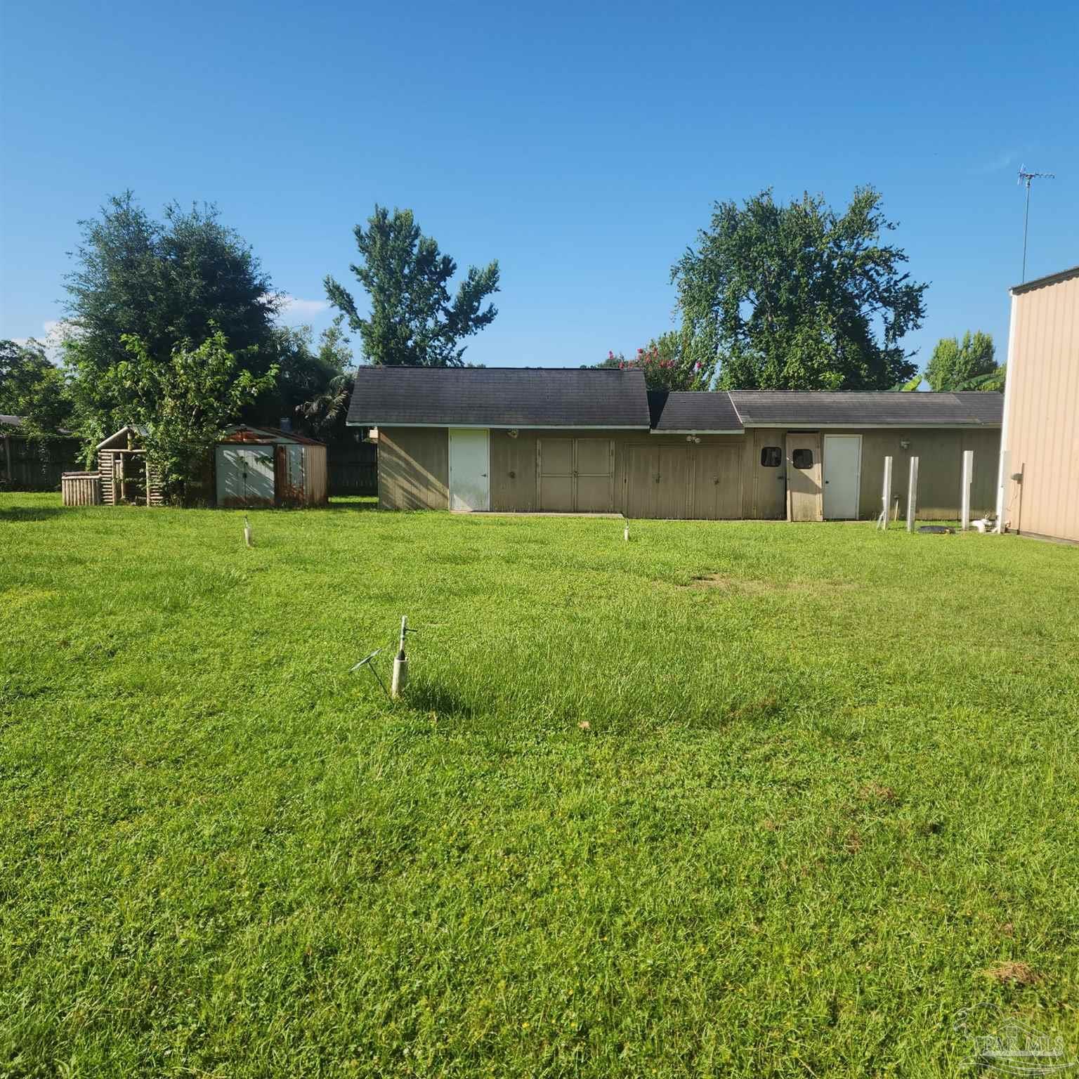 3217 Wallace Lake Road Pace, FL 32571 - Photo 16 of 17 a house that is sitting in the grass with large trees and plants