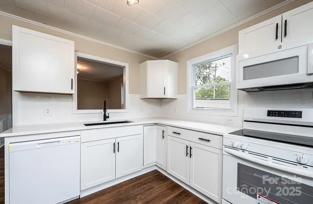 a kitchen with white cabinets appliances and a window