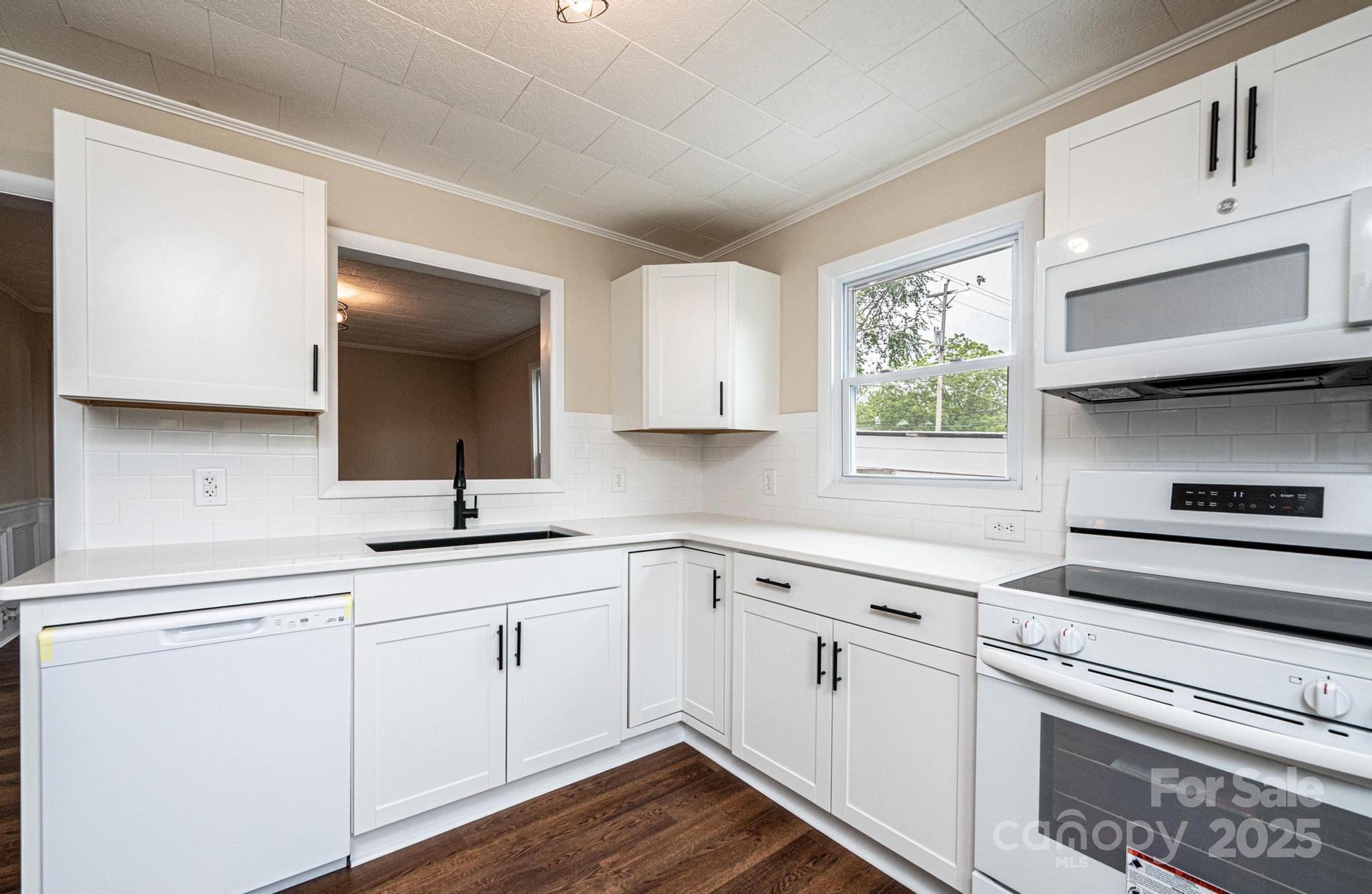 210 West 15th Street Newton, NC 28658 - Photo 16 of 43 a kitchen with white cabinets appliances and a window