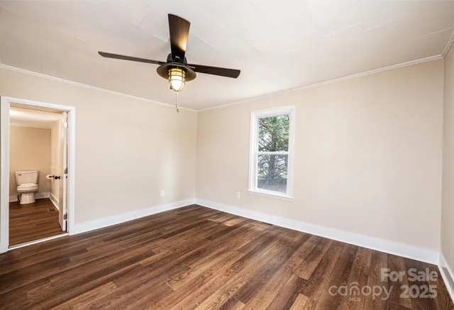 an empty room with wooden floor cabinet and windows