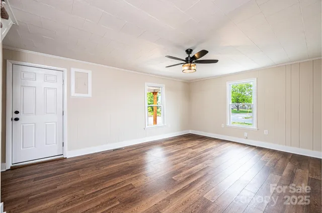 an empty room with wooden floor and windows