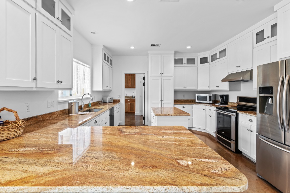 2321 Gentry Creek Road Menard, TX 76859 - Photo 14 of 35 a kitchen with stainless steel appliances granite countertop a stove top oven a sink a refrigerator and white cabinets