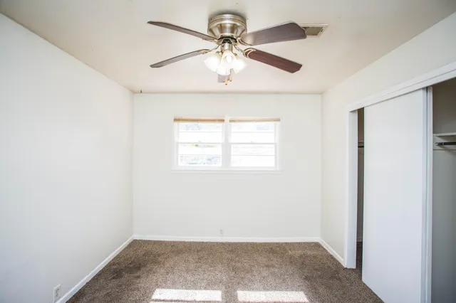 an empty room with windows and fan