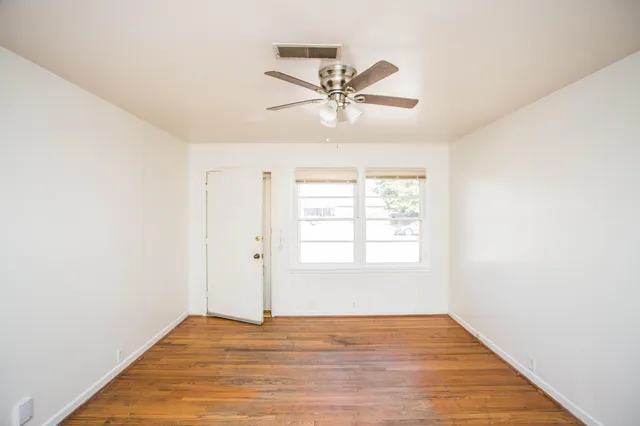 a view of an empty room with wooden floor and window
