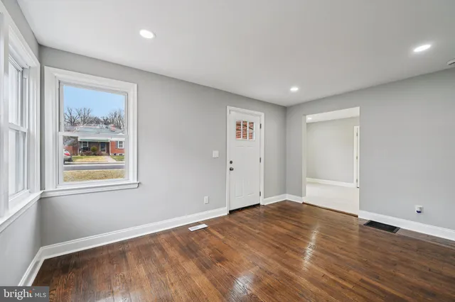 a view of empty room with wooden floor and window
