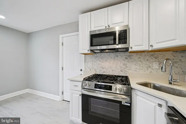 a kitchen with stainless steel appliances white cabinets and a stove top oven