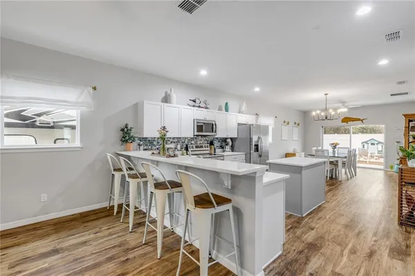 a living room with furniture and a dining table with wooden floor
