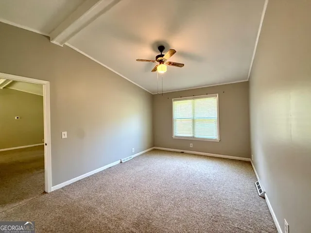 an empty room with windows and ceiling fan