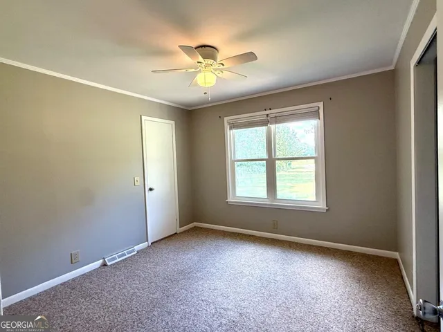 an empty room with windows and fan