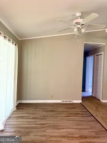 a view of a room with wooden floor and ceiling fan