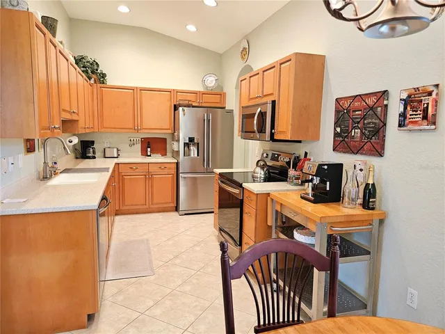 a kitchen with stainless steel appliances a stove a sink a refrigerator cabinets and a dining table
