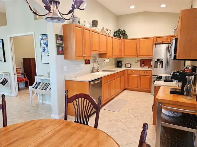 a kitchen with stainless steel appliances granite countertop a sink a stove a dining table and chairs with wooden floor