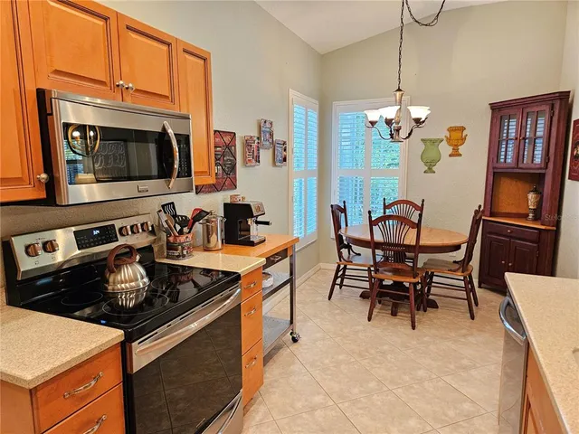 a kitchen with stainless steel appliances granite countertop a stove a sink dishwasher a dining table and chairs with wooden floor