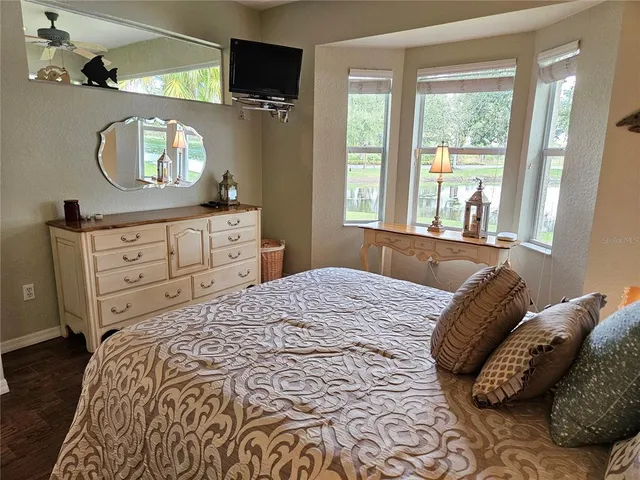 a bedroom with a bed and a flat tv screen on dresser