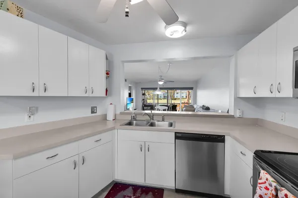 a kitchen with a sink dishwasher and white cabinets with wooden floor