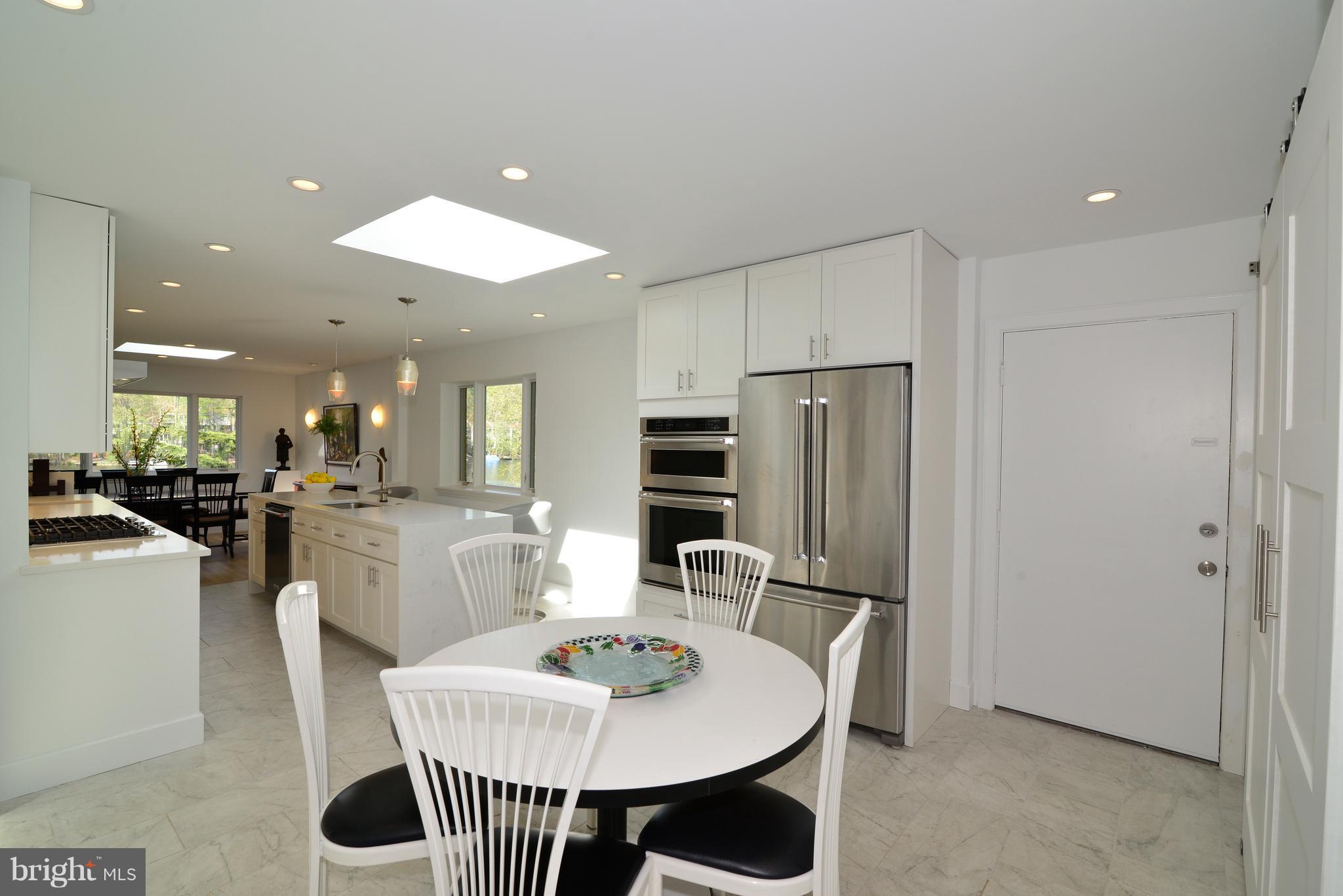 11316 South Shore Road Reston, VA 20190 - Photo 12 of 29 a kitchen with stainless steel appliances kitchen island granite countertop a dining table chairs and a refrigerator