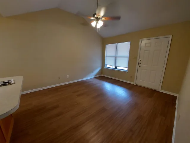 a view of empty room with wooden floor and fan